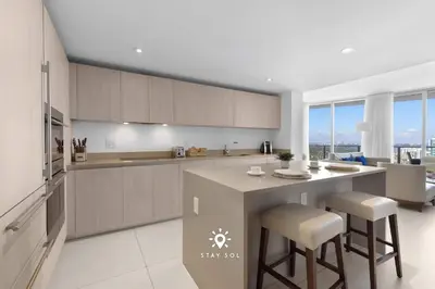 a kitchen with a counter and some chairs in it at Stunning 1BR Apt With Ocean View Balcony in Hollywood