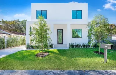 a white house with a tree in the yard at Luxe Pool House in North Miami Perfect for Groups in North Miami Beach