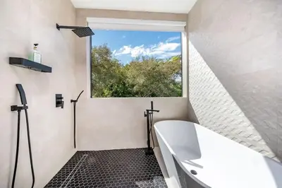 a bathroom with a white tub and a window at Luxe Pool House in North Miami Perfect for Groups in North Miami Beach