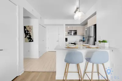 a white kitchen with two blue chairs and a counter at Stylish 1BR High Rise Retreat w Ocean View in Hallandale Beach