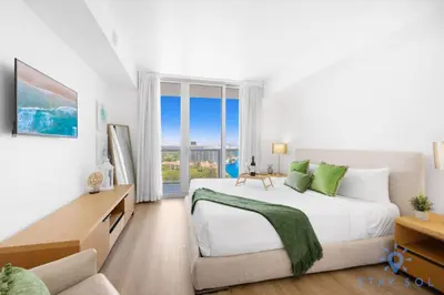 a white bedroom with a large bed and a window at Stylish 1BR High Rise Retreat w Ocean View in Hallandale Beach