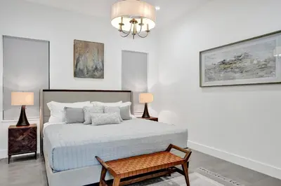 a white bedroom with a bed and a chandelier at New Luxe Contemporary Home 4BR-4BA with Heated Pool, Mini Golf, Pool table in Fort Lauderdale