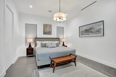 a white bedroom with a bed and a table at New Luxe Contemporary Home 4BR-4BA with Heated Pool, Mini Golf, Pool table in Fort Lauderdale