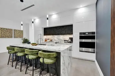 a kitchen with a bar with green stools at New Luxe Contemporary Home 4BR-4BA with Heated Pool, Mini Golf, Pool table in Fort Lauderdale