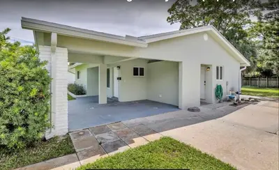 a small white house with a driveway at The Pines Hideaway-Your Home Away from Home in Fort Lauderdale
