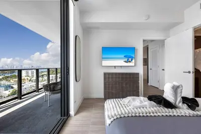a bedroom with a bed and a balcony with a tv at Chic Miami Retreat Stylish 2BR Gem for 5 in Miami Beach
