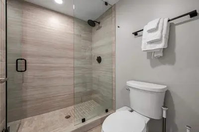 a bathroom with a toilet and a glass shower at Chic Miami Retreat Stylish 2BR Gem for 5 in Miami Beach