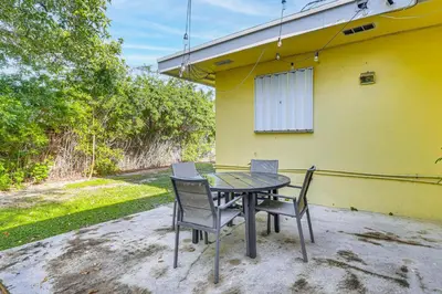 a table and chairs in front of a yellow house at Game Day Made Easy Home 3 Mi to Hard Rock Stadium in Miami Gardens
