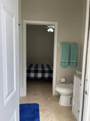 a bathroom with a toilet and blue towels at The Miami Lakes Pool House in Miami Lakes