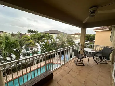 a balcony with a table and chairs and a pool at The Miami Lakes Pool House in Miami Lakes