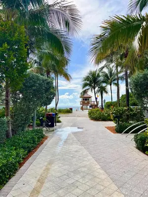 a walkway with palm trees and a gazebo at Modern 2 bedroom condo with heated pool, free parking spot at a 5 minute walk to the beach! in Sunny Isles Beach