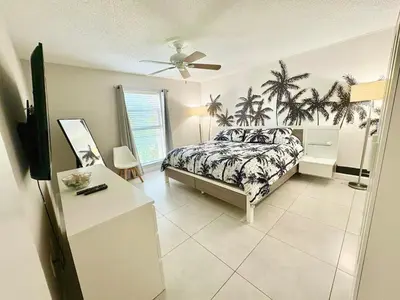 a bedroom with a bed with palm trees on it at Modern 2 bedroom condo with heated pool, free parking spot at a 5 minute walk to the beach! in Sunny Isles Beach