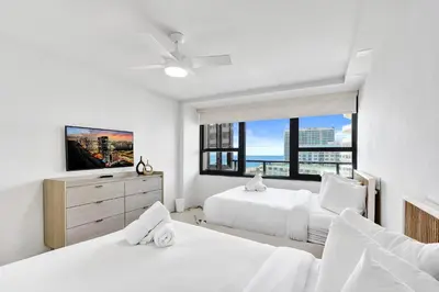 a white bedroom with two beds and a window at Luxury Oceanfront Condo 2BR 2.5BA with 700Sqft Terrace Sauna Resort Amenities and Pools 1501 in Miami Beach