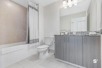 a bathroom with a toilet and a sink and a mirror at Doral 2BD Condo with Skyline Views and Fitness Center in Miami