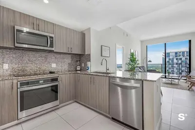 a kitchen with stainless steel appliances and a large window at Doral 2BD Condo with Skyline Views and Fitness Center in Miami