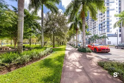 a red car parked on a street with palm trees at Studio Apt in Downtown Doral in Miami