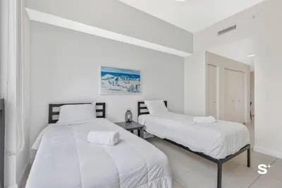 two beds in a room with white walls at Studio Apt in Downtown Doral in Miami