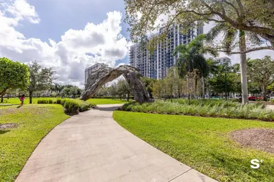 a path through a park with an arch in the middle at Modern 1BR in Downtown Doral - Free Parking and Wellness Amenities in Miami