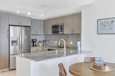 a kitchen with a stainless steel refrigerator and a table at Modern 1BR in Downtown Doral - Free Parking and Wellness Amenities in Miami