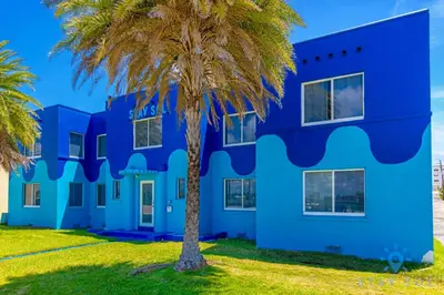 a blue building with a palm tree in front of it at 809 Complex in Hollywood