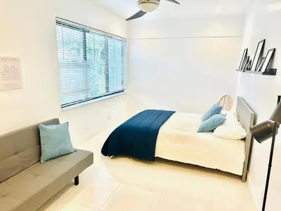 a bedroom with a bed and a couch in it at Palm Breeze Getaway in Hollywood