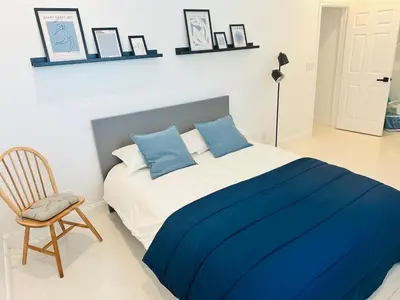 a bedroom with a bed with blue pillows and a chair at Palm Breeze Getaway in Hollywood