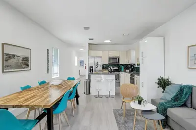 a kitchen and living room with a wooden table and blue chairs at Palm Breeze Retreat in Hollywood
