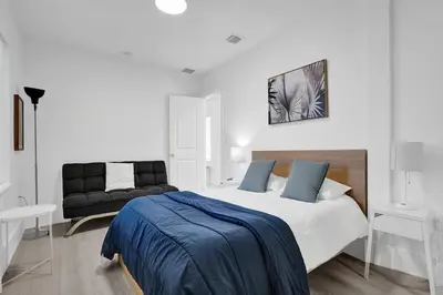 a white bedroom with a bed and a couch at Palm Breeze Retreat in Hollywood