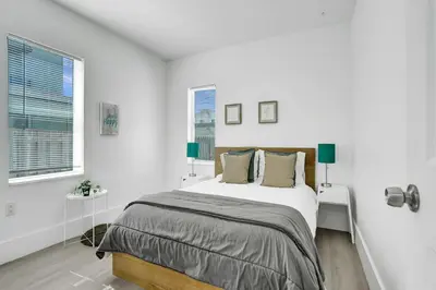 a white bedroom with a large bed and two windows at Palm Breeze Retreat in Hollywood