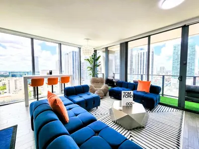 a living room with blue furniture and large windows at 3BR Skyline Luxury with a 100 inch TV, Balcony & Prime Miami Location in Miami