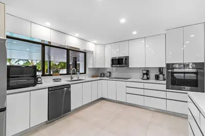 a white kitchen with white cabinets and appliances at Lakefront Villa Tropical Backy in North Miami Beach