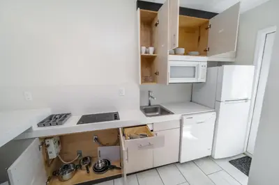 a kitchen with white cabinets and a white refrigerator at Casa Colaretta By At Mine Hospitality in Miami Beach
