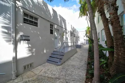 a white building with stairs next to a palm tree at Casa Colaretta By At Mine Hospitality in Miami Beach