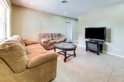 a living room with a couch and a table and a flat screen tv at 3 Mi to Dania Beach Pier Convenient Apartment! in Dania Beach