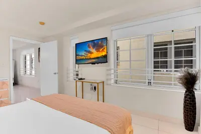 a bedroom with a bed and a tv on the wall at 2BR Art Deco Retreat Steps Away from the Beach in Miami Beach
