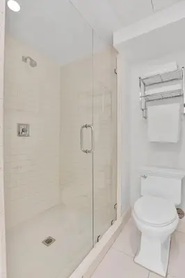 a bathroom with a toilet and a glass shower at 2BR Art Deco Retreat Steps Away from the Beach in Miami Beach