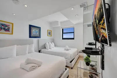 a bedroom with two beds and a flat screen tv at Stylish Oceanfront 2BR 1 and a half BA Condo with Resort Amenities Pools Gym Sauna 1402 in Miami Beach