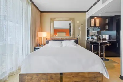 a bedroom with a large white bed and a kitchen at Luxury Suite - 3 Min Walk to Miami Beach in Miami Beach