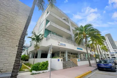 a building with palm trees in front of it at Luxury Suite - 3 Min Walk to Miami Beach in Miami Beach