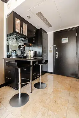 a kitchen with black cabinets and a bar with stools at Luxury Suite - 3 Min Walk to Miami Beach in Miami Beach