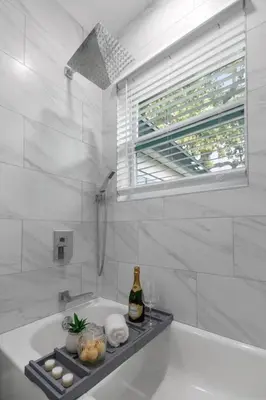 a white bathroom with a bath tub with a bottle of champagne at Renovated Home in Hollywood in Hollywood