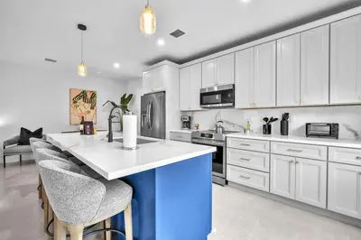 a kitchen with white cabinets and a blue island at Casa Bella - New & Stylish Family-Friendly Home in Miami