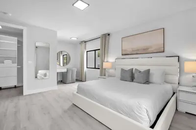 a white bedroom with a large bed and a bathroom at Casa Bella - New & Stylish Family-Friendly Home in Miami