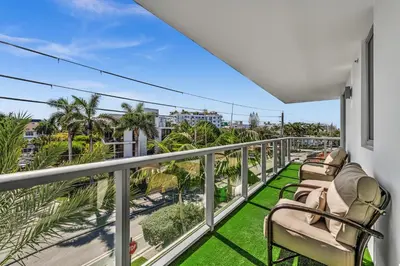 a balcony with chairs and a view of palm trees at Waterfront Luxury Kosher Condo with Rooftop Pool, Bay Harbor Islands in Miami Beach