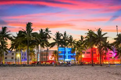 a beach with palm trees and buildings at sunset at 713 Miami Beach Apartments in Miami Beach
