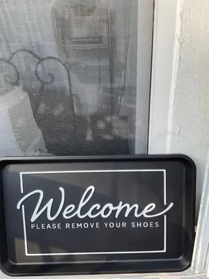 a sign in a window that reads welcome please remove your shoes at Lodgings by Lisa in Cooper City