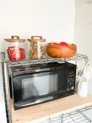 a microwave on a shelf with vegetables on top of it at Lodgings by Lisa in Cooper City