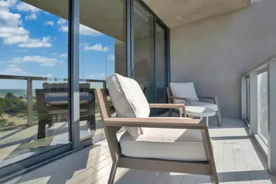 a balcony with two chairs and a table and windows at Oceanfront Elegance at W Hotel in Miami Beach
