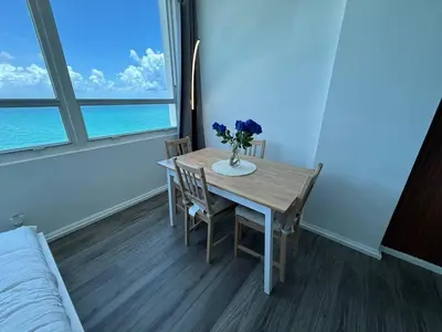 a dining room table with a vase of flowers on it at 1701 - Studio Ocean Front Free Parking Pool in Miami Beach
