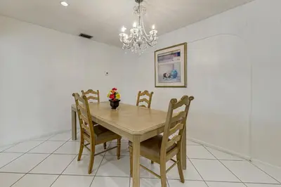 a dining room table with chairs and a chandelier at Canal-Front Gem with Pool 3 Mi to Hard Rock Stadium in Miramar